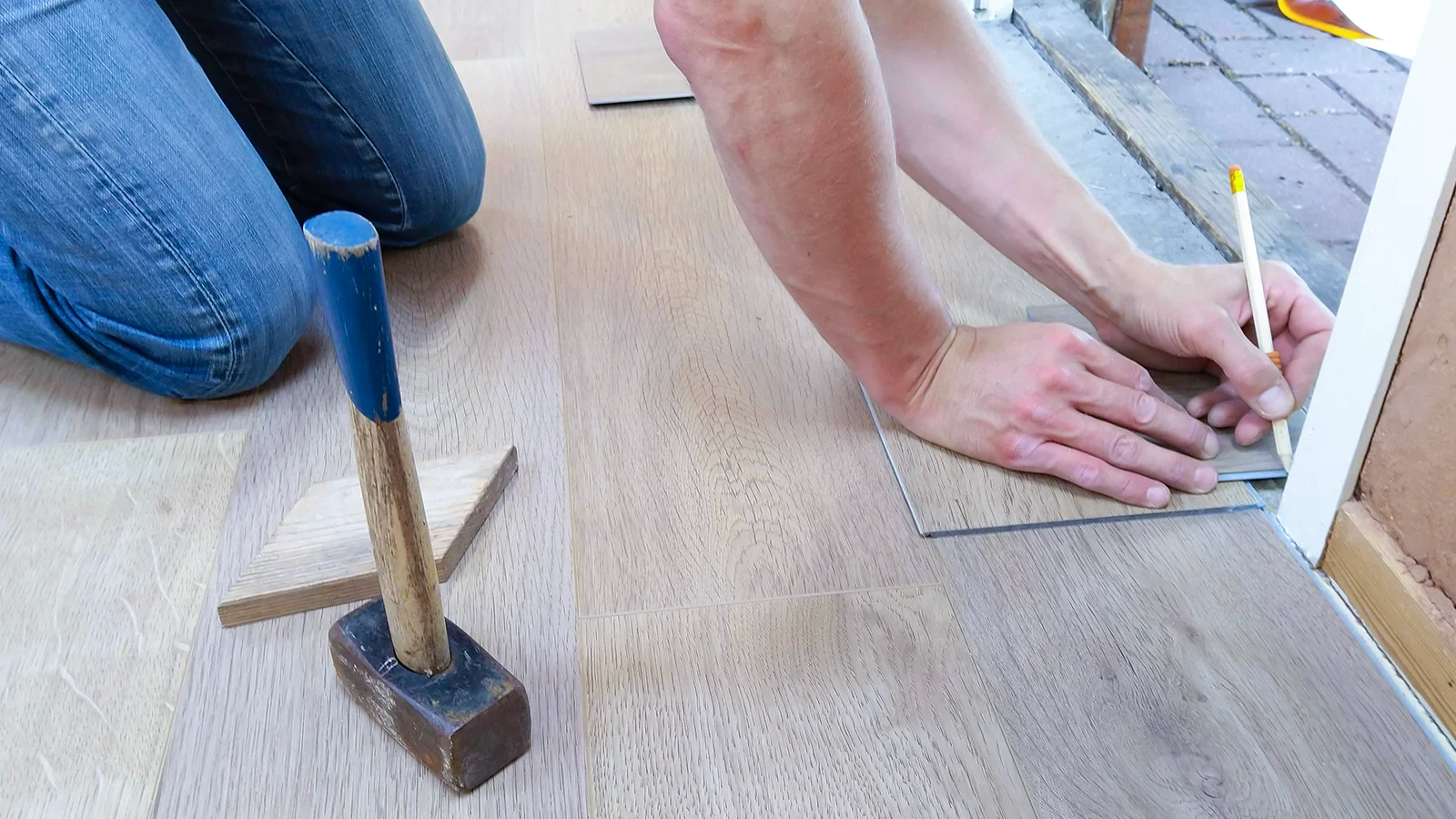Floor installer slotting in wood panels near the door