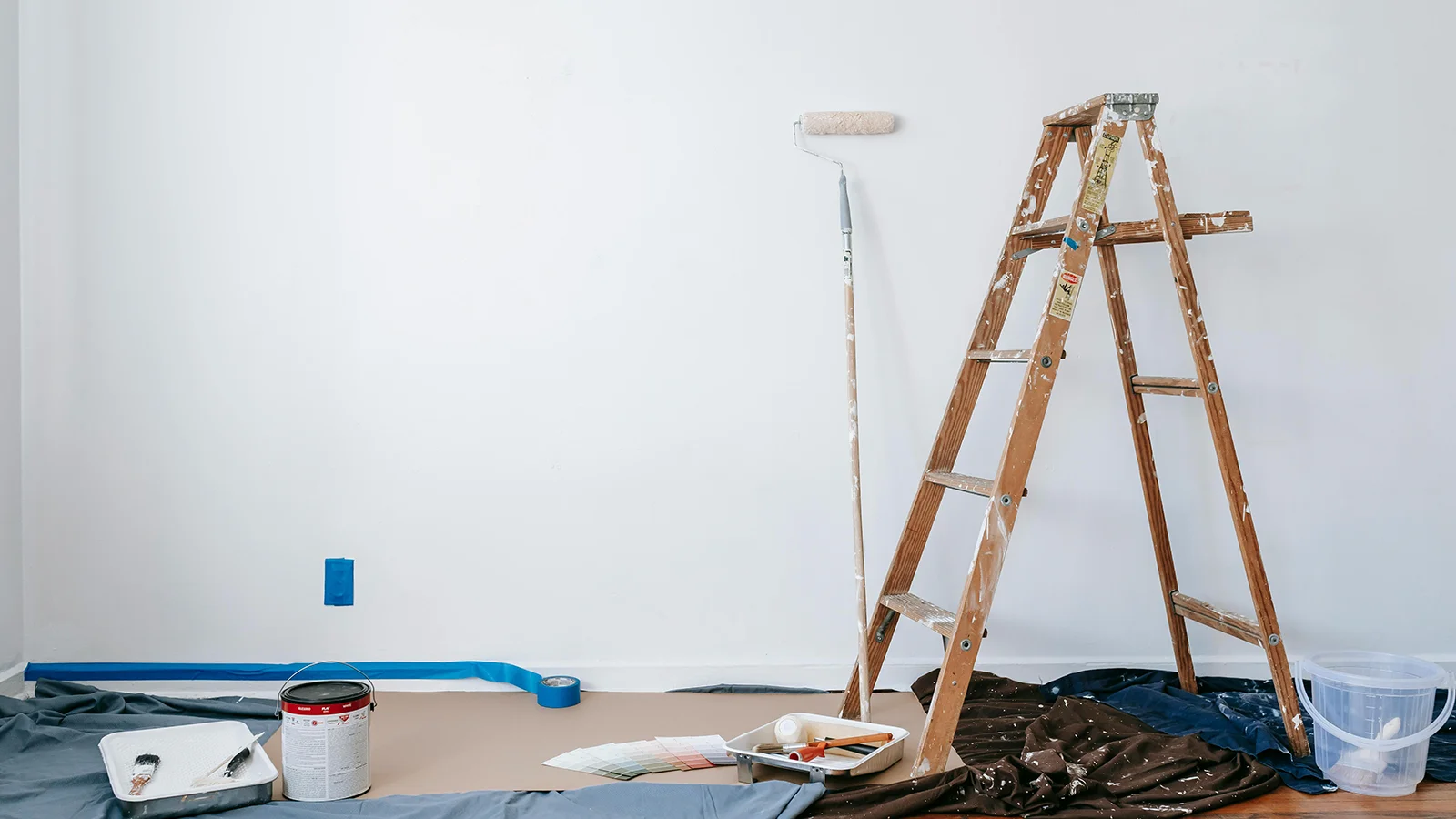A fresh painted blue wall with painters tools ready for pickup