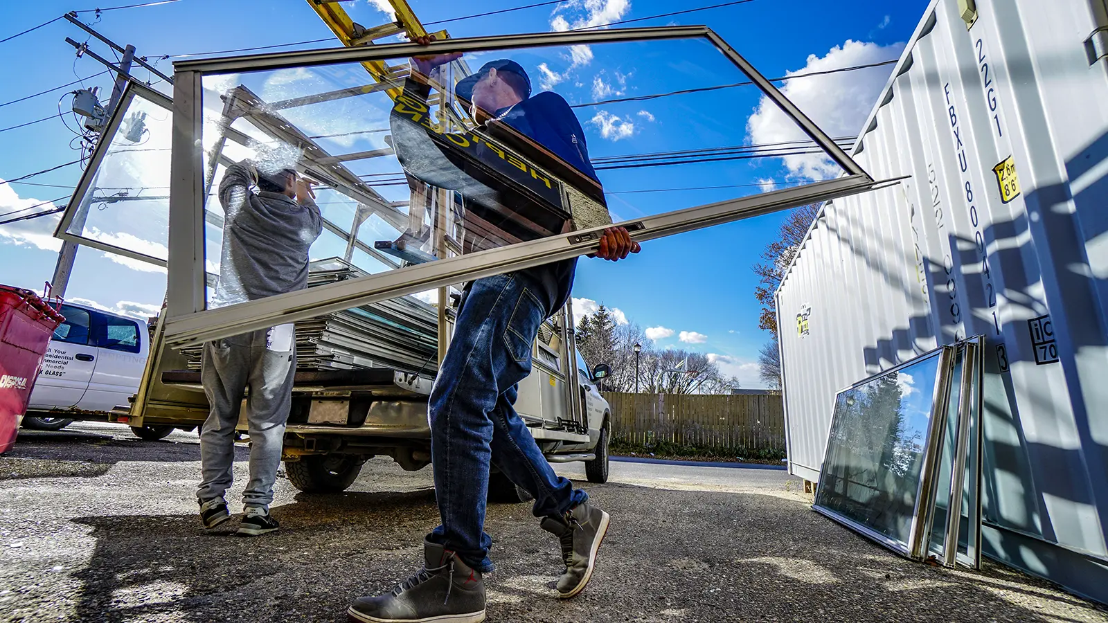 Window installer loading patio door pane into truck